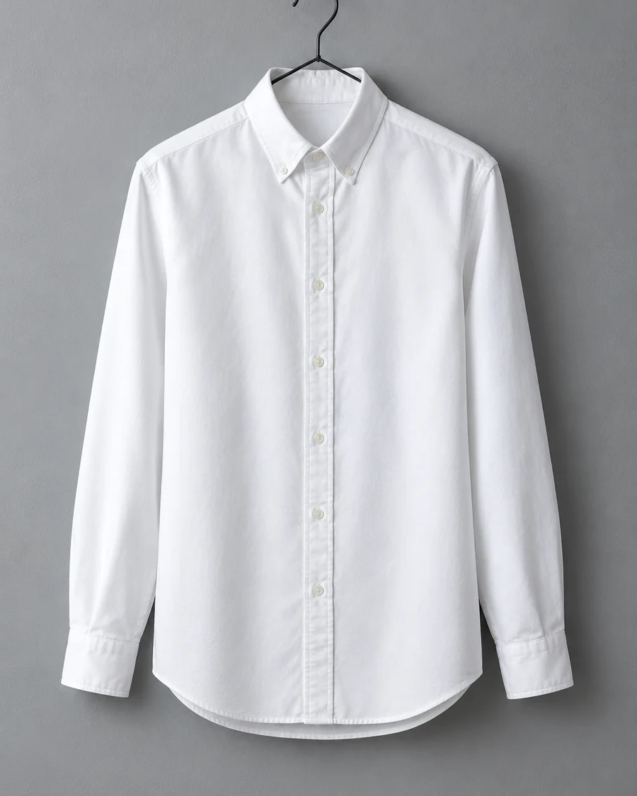 Camisa oxford blanca de cuello abotonado colgada en una percha negra de metal